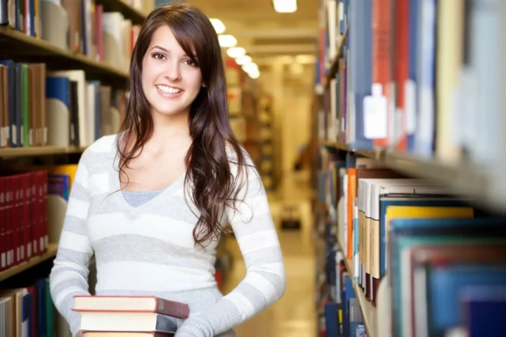 Woman in library carrying books.